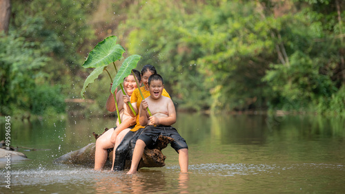 Fototapeta Naklejka Na Ścianę i Meble -  Happy Country Boy And Girl smiling Playing Water at the River in asian.
