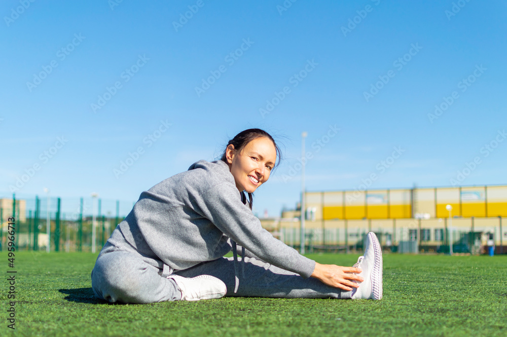 Woman doing gymnastics outdoors.Fitness woman stretch legs after run workout training outdoor. Woman doing gymnastics outdoors.Fitness woman stretch legs after run workout training outdoor.