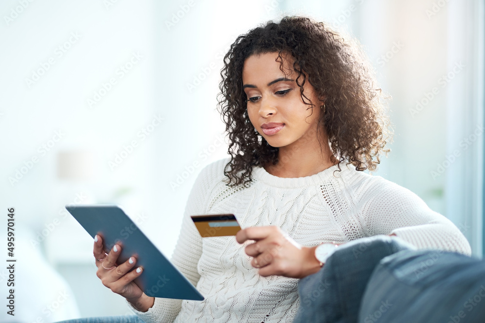Make smarter purchases. Shot of a young woman holding her credit card while using a digital tablet. Make smarter purchases. Shot of a young woman holding her credit card while using a digital tablet.