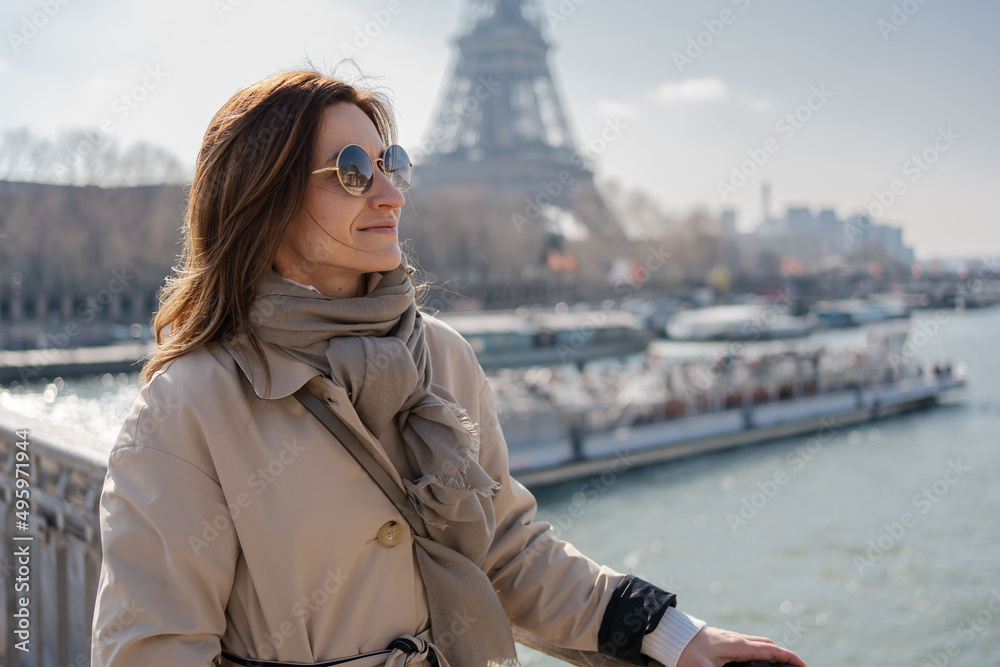 Portrait of happy young elegant woman on embankment near Eiffel tower in Paris, France having walking tour.Girl tourist walking in front of the Eiffel Tower .