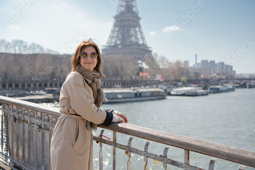 Portrait of happy young elegant woman on embankment near Eiffel tower in Paris, France having walking tour.Girl tourist walking in front of the Eiffel Tower . © Julija