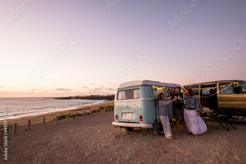 Group of friends celebrate toasting in summer travel holiday vacation. Camper van lifestyle. people man and women together having fun in outdoor leisure activity. Ocean view in free camp site photo