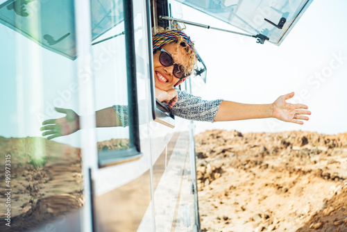 Cheerful happy tourist woman smile and do hallo gesture with hand outside the window of modern camper van caravan vehicle. Renting motor home for summer travel holiday vacation people