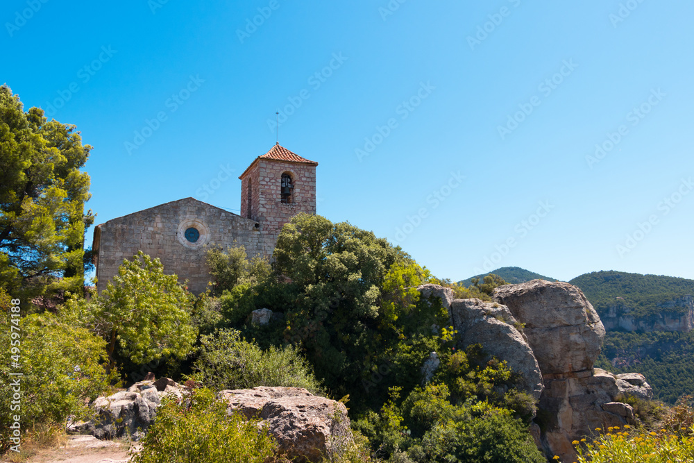 Siurana, Tarragona, Spain - July 2021 - side view of the Church of the village in a Summer day with blue sky
