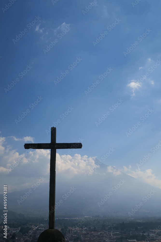 The amzing view from the mirador with the holy cross in front and the Acatenango volcano in the background from the city of Antigua in Guatemala in Central America on a sunny day