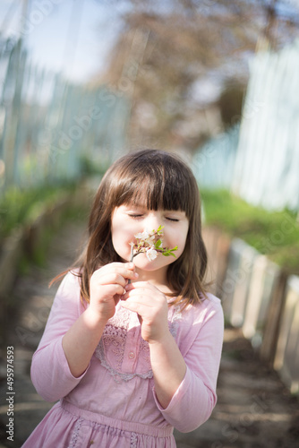 dziewczynka zachwycona wiosną podziwia i wącha kwiaty