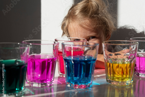 Colored drink in the glasses with dye. Creativity, fun and play with autistic child. Colorful experiment with kid in kindergarten. Closeup. 
