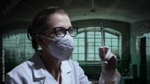 Crazy caucasian nurse about to inject with a glass syringe in an abandoned asylum. Close-up in flickering lights. High quality 4k footage