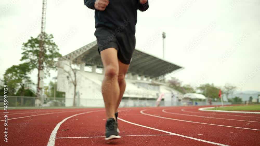 Attractive Young chinese man wearing sportswear running on track at sport stadium. Fit man jogging outdoor cross the finish line. Exercise in the morning. Healthy and active lifestyle concept. Attractive Young chinese man wearing sportswear running on track at sport stadium. Fit man jogging outdoor cross the finish line. Exercise in the morning. Healthy and active lifestyle concept.