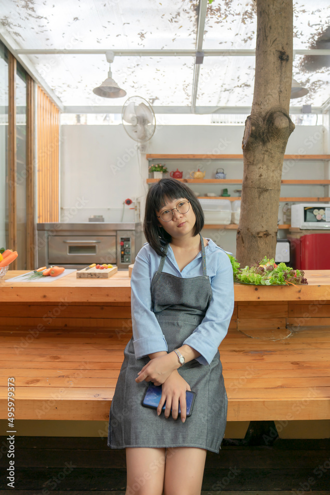 Asian glasses Woman thinks for lunch menu in front of wooden counter kitchen. Thailand style. Asian glasses Woman thinks for lunch menu in front of wooden counter kitchen. Thailand style.
