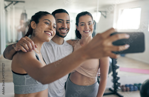 Online to spread some fitness inspiration. Shot of three young athletes taking a selfie while standing together in the gym.