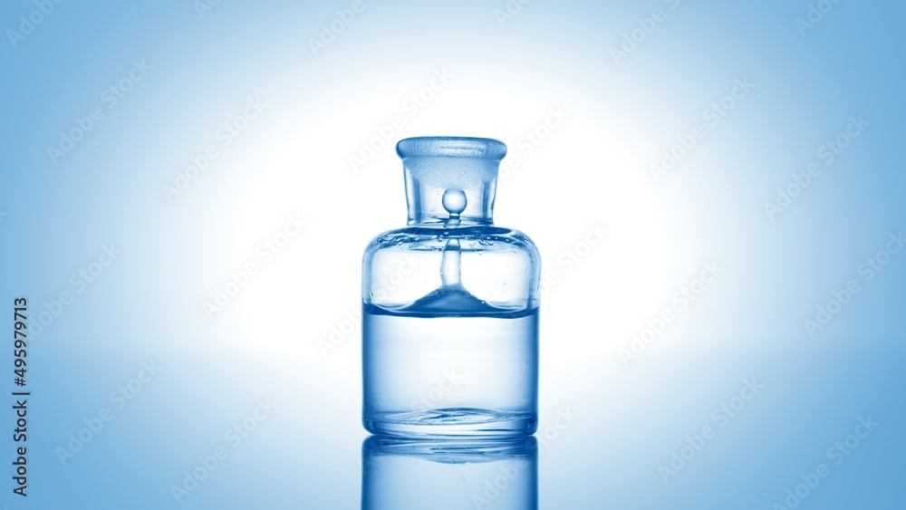 Blue drop falls into old fashioned bottle with blue clear liquid and makes column inside it on pale blue background | Abstract skin care cosmetics formulating concept Blue drop falls into old fashioned bottle with blue clear liquid and makes column inside it on pale blue background | Abstract skin care cosmetics formulating concept