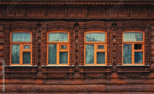 Four windows with carving in the wall of an old wooden house