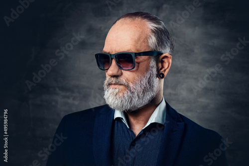 Tablou pe pânză Bearded old man with sunglasses posing against dark background