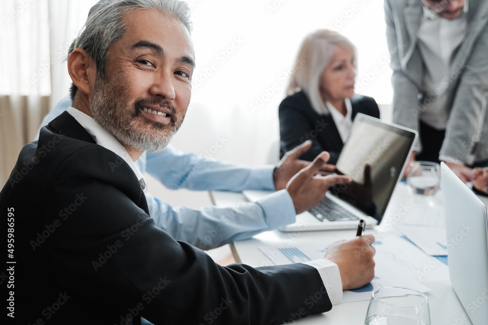 Business senior Asian man smiling at camera while working inside bank office - Focus on face