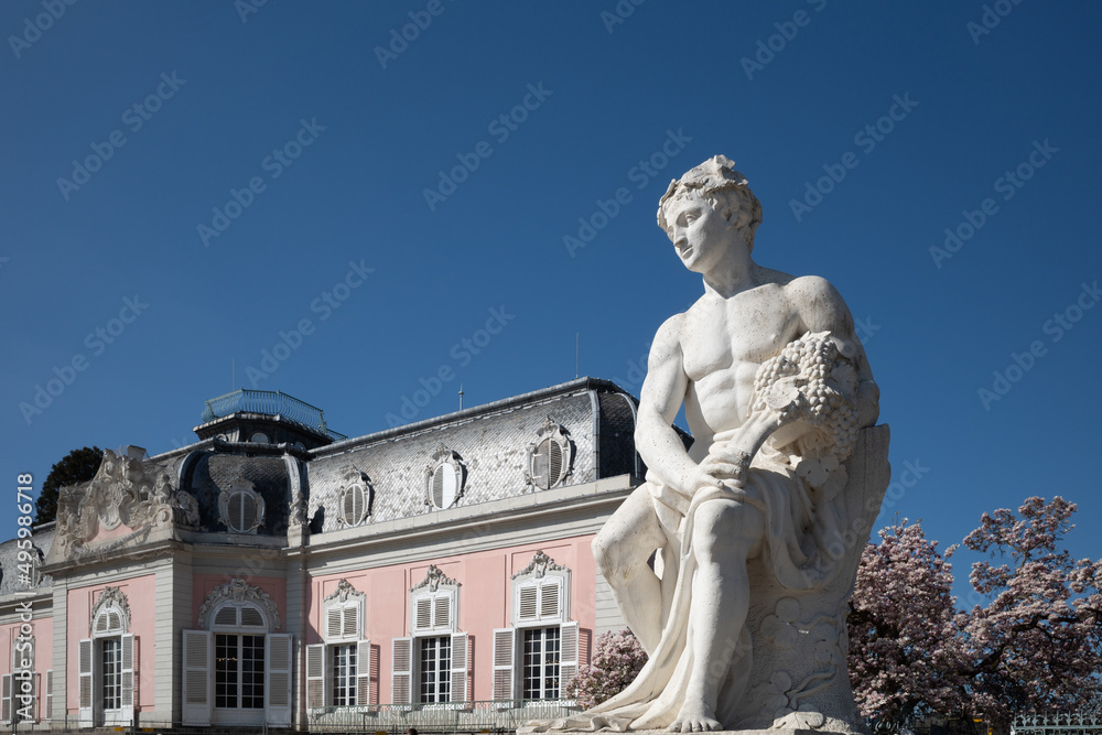 Selective focus at white classical male human sculpture and background of Schloss Benrath, old classic residence palace. Selective focus at white classical male human sculpture and background of Schloss Benrath, old classic residence palace.