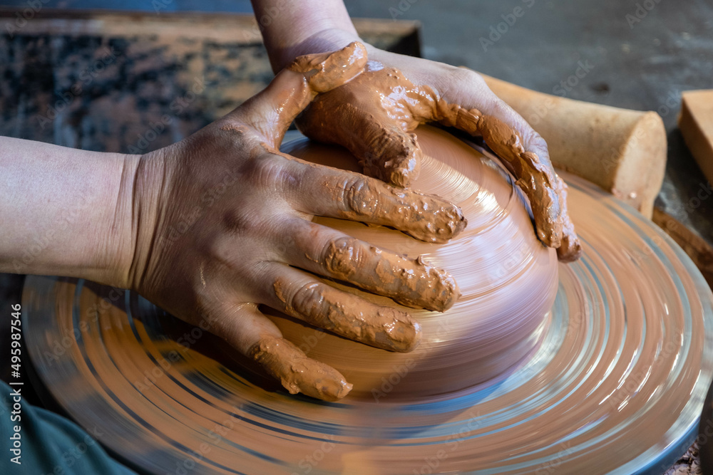 Hands of a potter at work. Potter making ceramic mug on the pottery wheel.