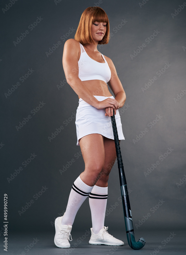 Dress like a champion and youll be seen as one. Studio shot of an attractive young woman posing with a hockey stick against a grey background. Dress like a champion and youll be seen as one. Studio shot of an attractive young woman posing with a hockey stick against a grey background.