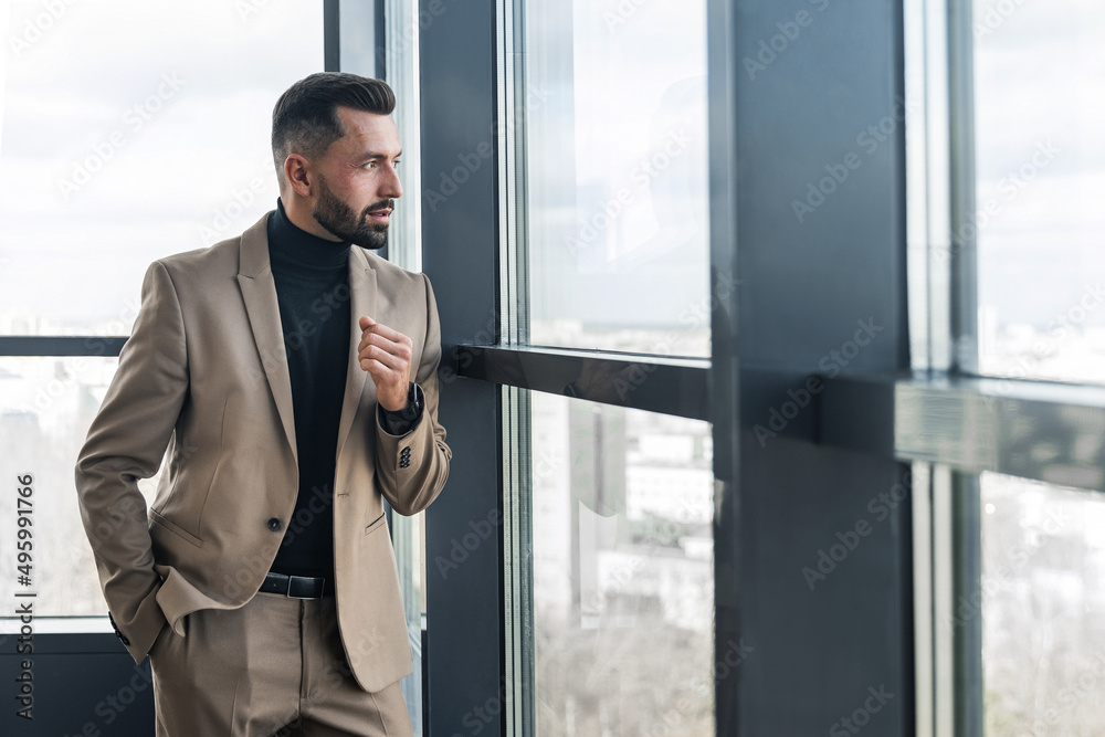 Handsome businessman looking out the window in the office Handsome businessman looking out the window in the office