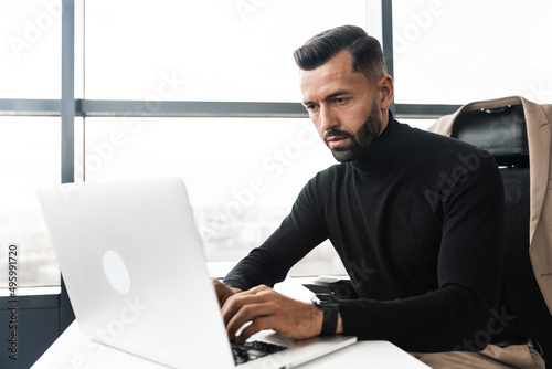 Focused businessman working on laptop while sitting in office © uladzislaulineu