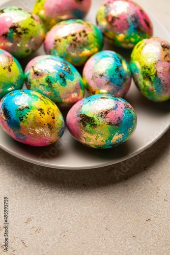 Easter eggs trendy colored blue, yellow, pink and golden in plate on light background. Happy Easter card with copy space for text. Minimal style. Selective focus.