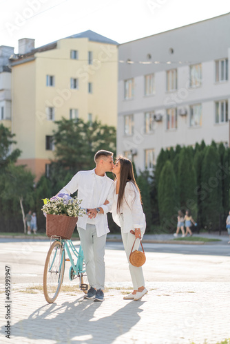 loving couple walks around the city with a bicycle and a basket of flowers