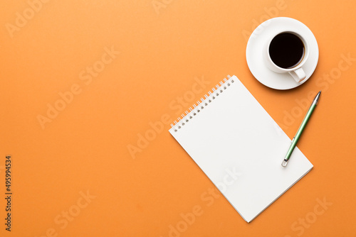 Modern office desk table with notebook and other supplies with cup of coffee. Blank notebook page for you design. Top view, flat lay