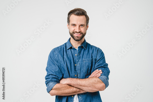 Confident caucasian young man in casual denim clothes with arms crossed looking at camera with toothy smile isolated in white background photo