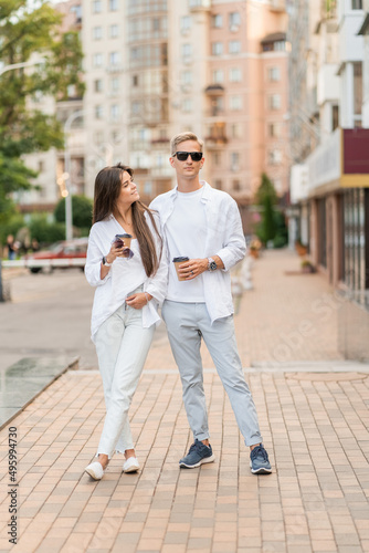 guy with a girl in white clothes walks around the city and drinks coffee © Olga
