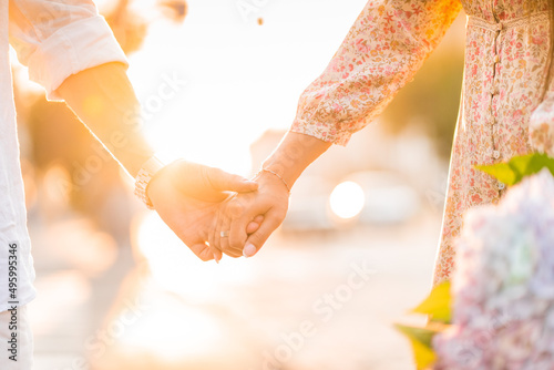 Hands of a loving couple on a sunset background