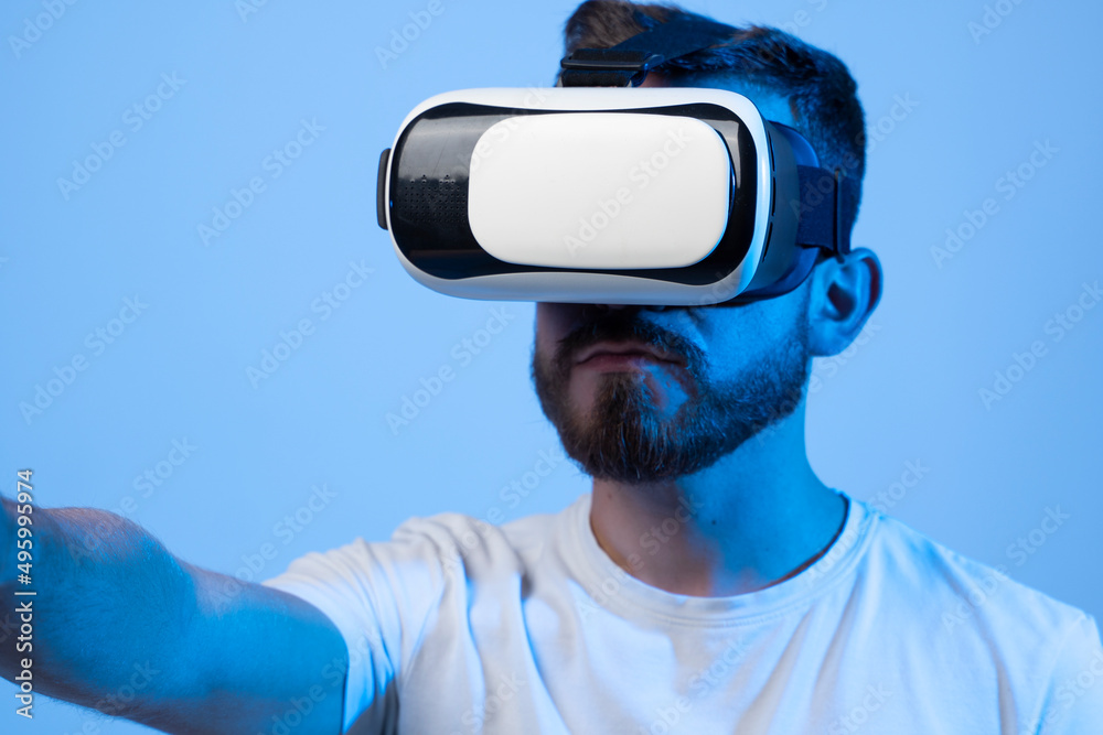 Young man using VR headset helmet to play simulation game. Watching virtual reality 3d video. Bearded man in VR goggles looking around. Young man using VR headset helmet to play simulation game. Watching virtual reality 3d video. Bearded man in VR goggles looking around.