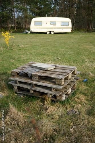 Gestapelte Europaletten aus Holz auf grünem Rasen mit Wohnwagen für Vanlife und Camping auf dem Campingplatz am Segelflugplatz Oerlinghausen bei Bielefeld im Teutoburger Wald in Ostwestfalen-Lippe photo