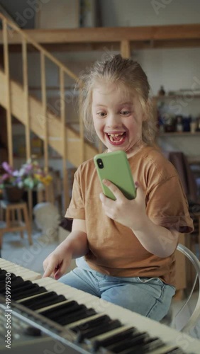 The girl plays the synthesizer, makes faces and takes a selfie