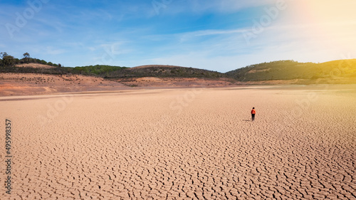Silhouette of a man on a sandy cracked empty not fertile land during a drought. The concept of ecological catastrophe on the planet. Sunny day