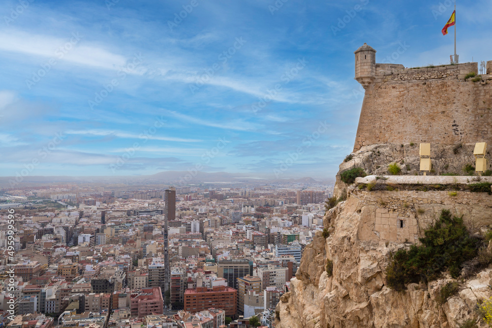 Wide angle view of Alicante, Spain Panoramic view of Postiguet beach, city and harbour. Mixed view of the modern city and the ruined walls and towers of Santa Barbara Castle.