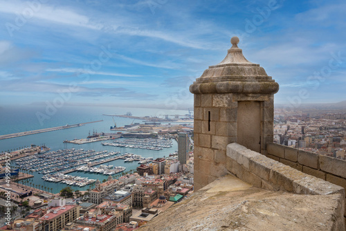 Wide angle view of Alicante, Spain Panoramic view of Postiguet beach, city and harbour. Mixed view of the modern city and the ruined walls and towers of Santa Barbara Castle. photo