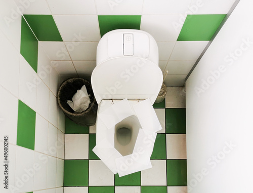 Napkins on the toilet seat in a public restroom. Toilet paper on the toilet seat.
