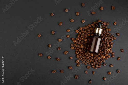 Brown bottle with dropper with a beauty serum on a black background on coffee beans. Glass packaging for cosmetic product, caffeine extract. Skin care, hydration and nutrition with collagen. photo