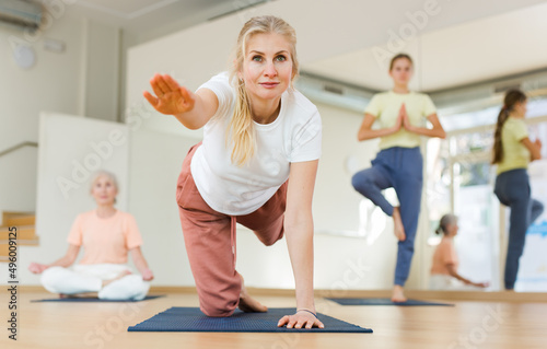 Portrait of positive adult woman training stretching workout in modern studio