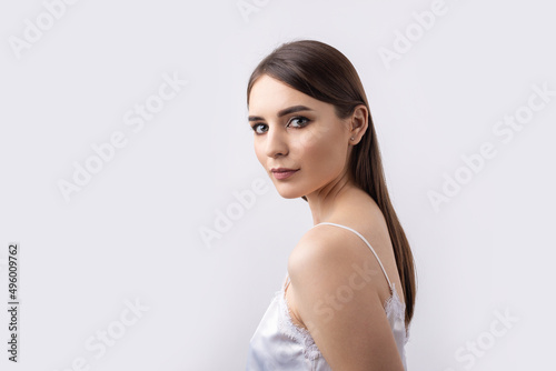 Beautiful smiling woman with clean skin, natural make-up and white teeth on a gray background