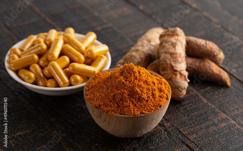 Ground Turmeric Capsules form on a Wooden Table