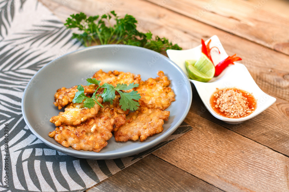 Corn Fritters With chili sauce placed on a wooden table Corn Fritters With chili sauce placed on a wooden table