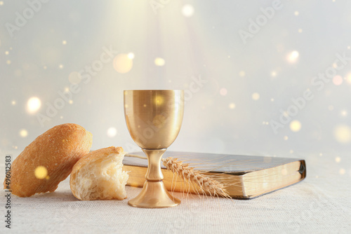 Valokuva Chalice of wine with bread and Bible on light background