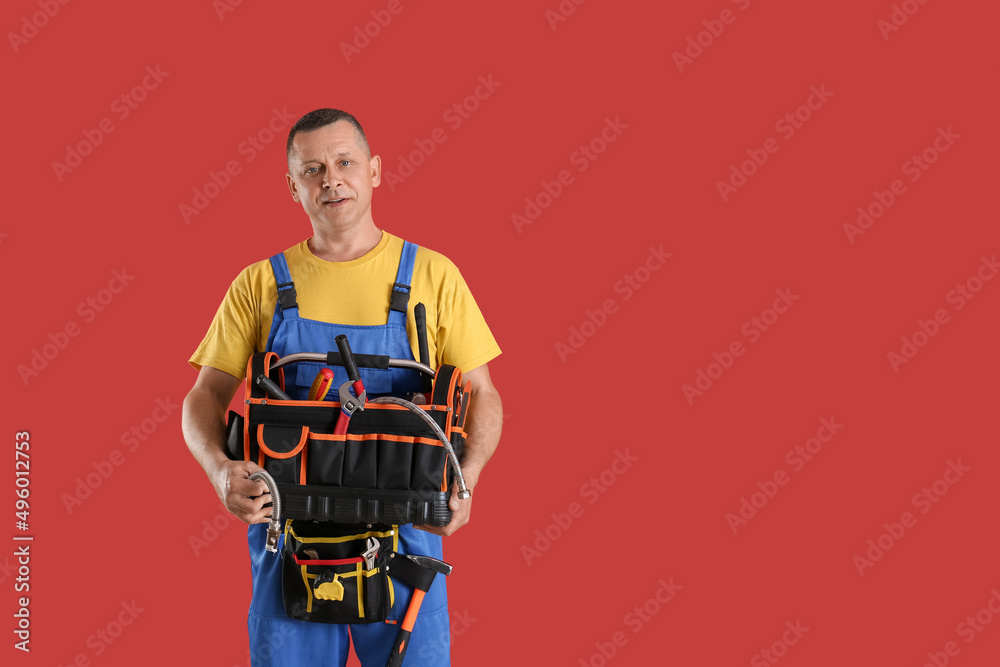 Handsome plumber with tools bag on color background Handsome plumber with tools bag on color background