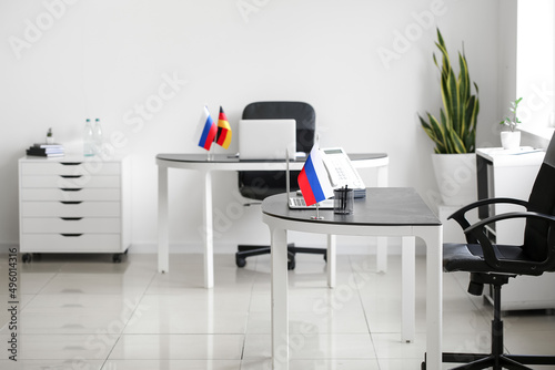 Russian flag  stationery holder  laptop and landline phone on table in office