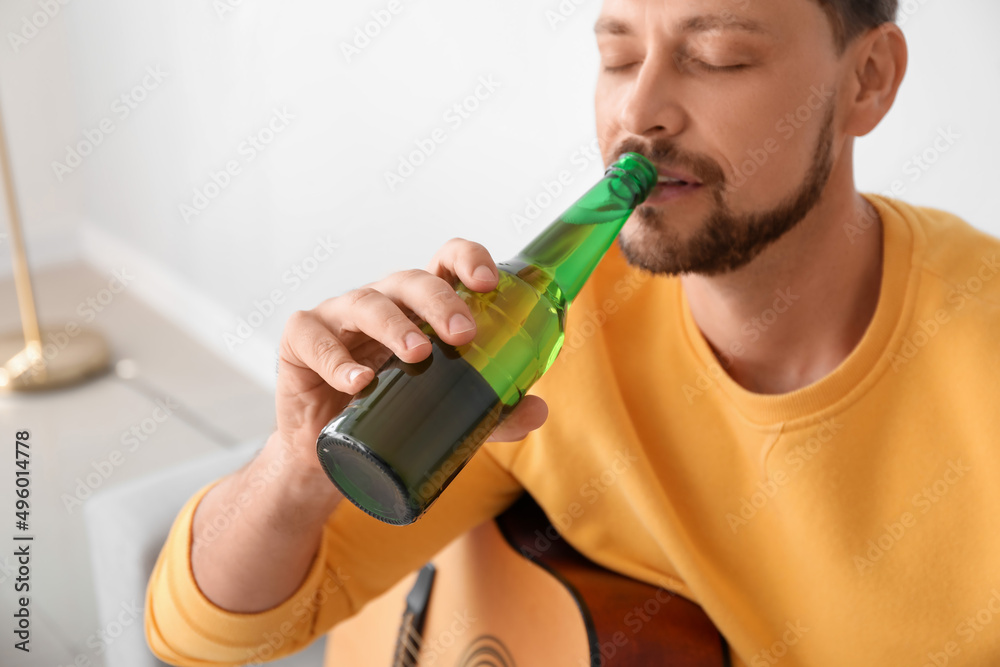 Handsome man drinking beer at home