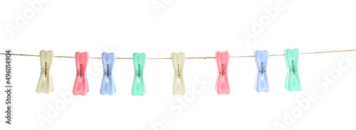 Plastic clothes pins hanging on rope against white background