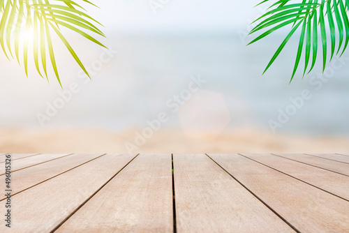 Empty wooden table in front of blurred beautiful view of the sea, sand, sunlight, palm tree background of nature with copy space in summer. Can be used for display or montage for show your products.