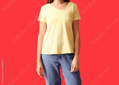 Young woman in blank t-shirt on color background