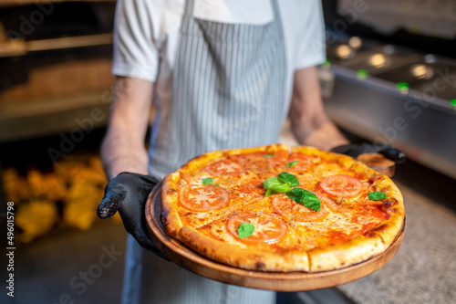 A chef holding a big pizza in his hands